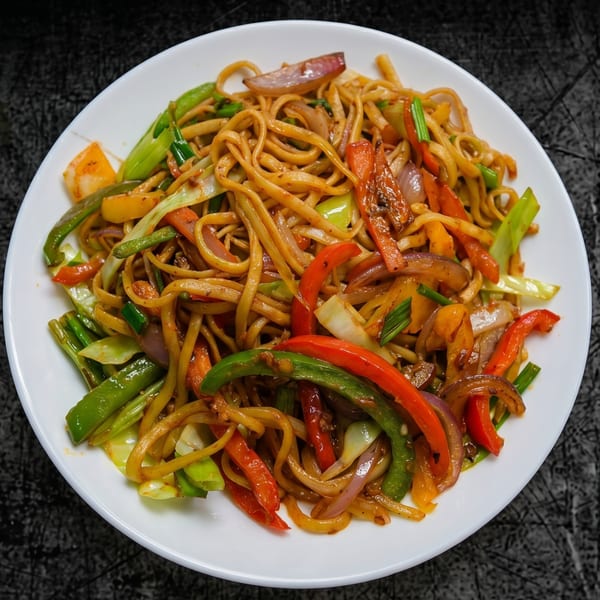 A white plate filled with stir-fried noodles, colorful bell peppers, onions, and green vegetables.