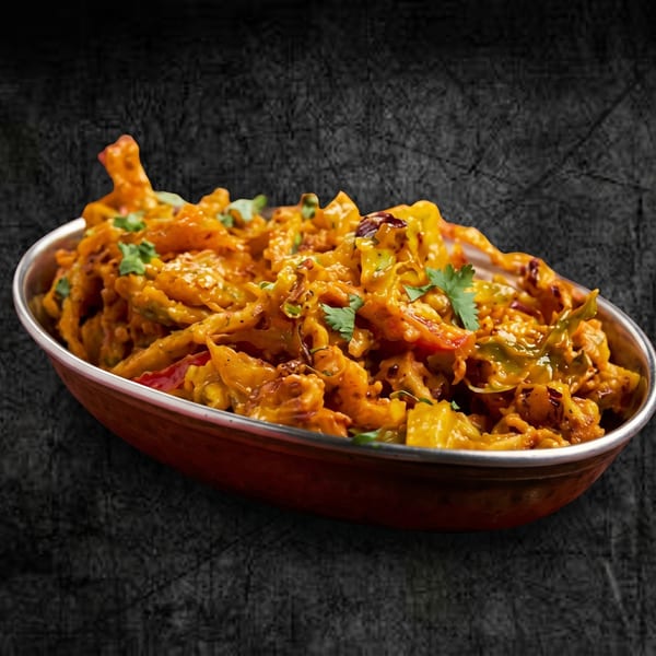 Close-up of a copper bowl filled with vibrant orange pakora, garnished with fresh cilantro.